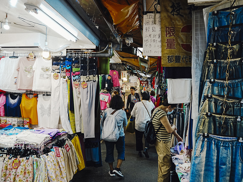 แผงขายเสื้อผ้าและร้านค้าเก่าแก่ภายในตรอกซอกซอยของตลาดเฉิงจง (Chengzhong Market) สะท้อนวิถีชีวิตประจำวันและบรรยากาศแบบดั้งเดิมของไทเปในอดีต