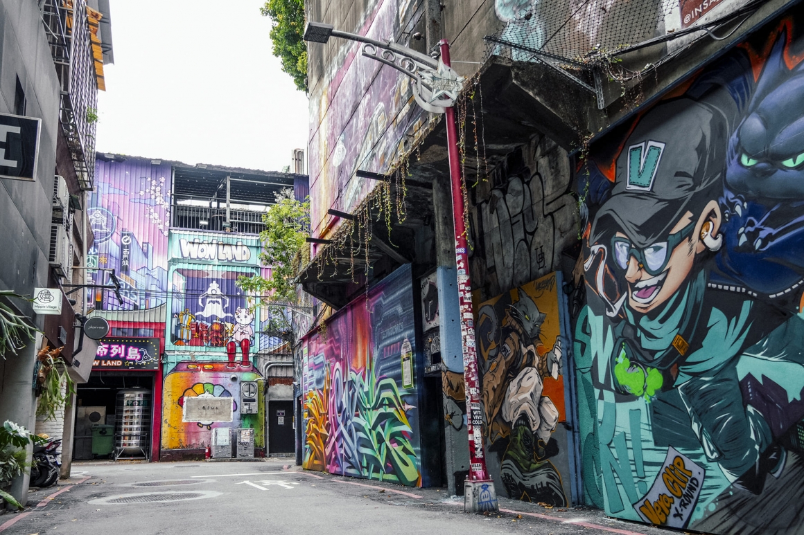 台北西門町美國街的特色拍照街景,巷弄兩側可見大型動漫塗鴉與彩色街頭藝術,展現西門町鮮明的潮流文化。